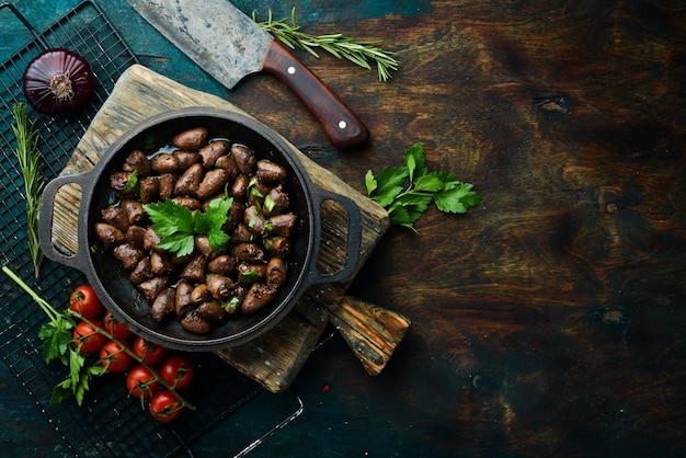 Fried chicken hearts with parsley and spices in a metal pan Top view Free space for text