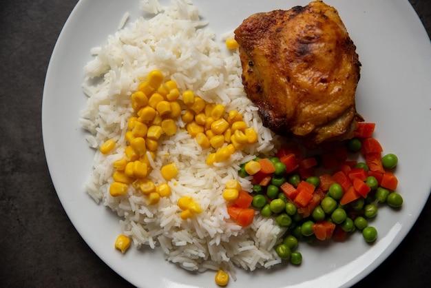 Fried chicken leg with rice corn carrots and peas