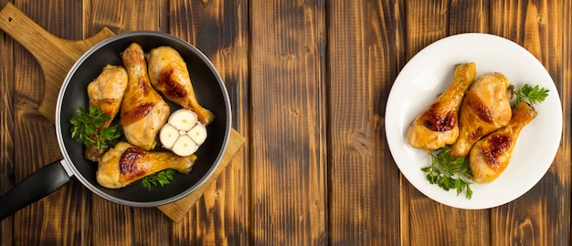 Cosce di pollo fritte in padella e piatto bianco sullo sfondo di legno vista dall'alto copia spazio