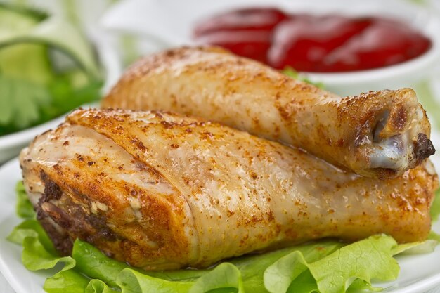 Fried chicken legs with cucumber salad and sauce closeup