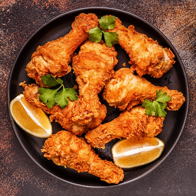 Photo fried chicken legs with lemon and parsley