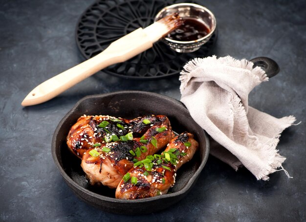 Fried chicken legs with teriyaki sauce in a frying pan