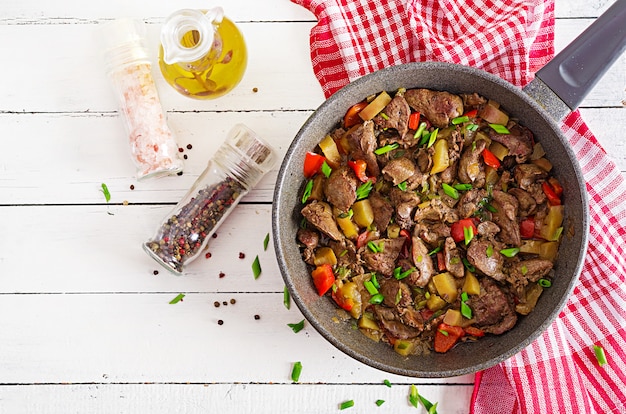 Fried chicken liver with apples and paprika in pan. 