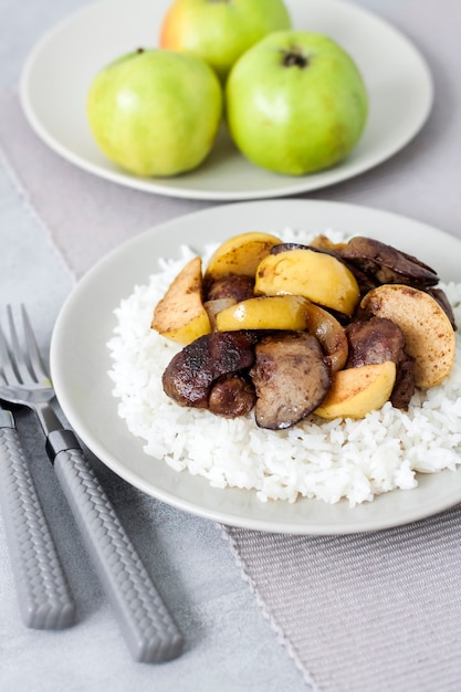 Fried chicken liver with apples served with white rice on a plate.