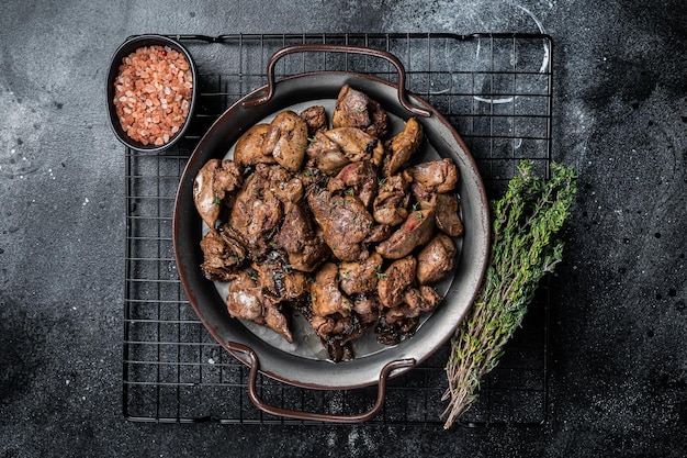 Photo fried chicken liver with onions and herbs black background top view