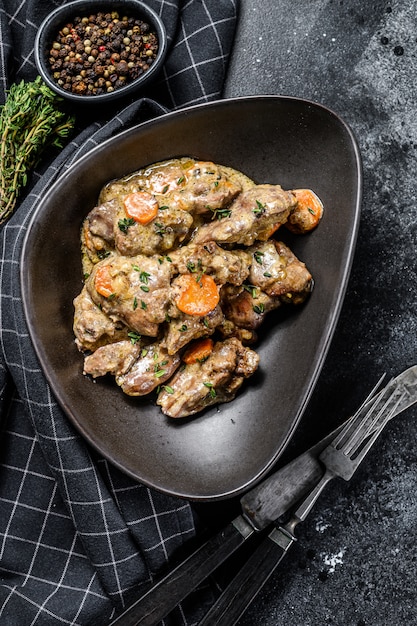 Foto fegato di pollo fritto con le cipolle e le erbe sul nero. vista dall'alto