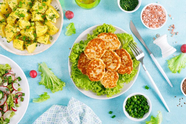 Fried chicken meat cutlets fresh vegetable salad with radish lettuce and cucumber boiled new potato with butter dill and green onion for lunch