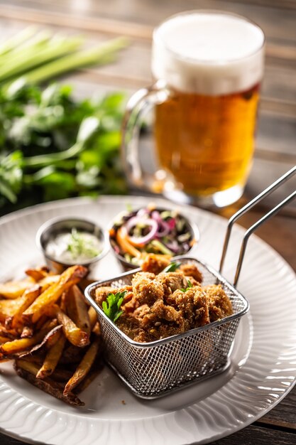 Fried chicken nuggets with french fries, dip, salad and beer.