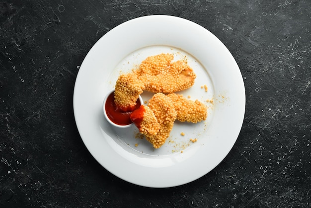 Fried chicken nuggets with ketchup sauce on a plate Top view