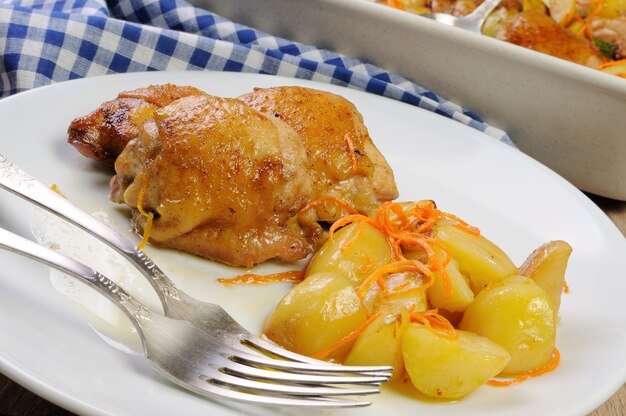 Fried chicken pieces with boiled potatoes and carrots on a plate