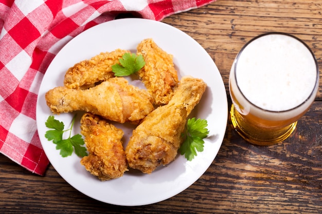 Fried chicken plate and glass of beer on a wooden table