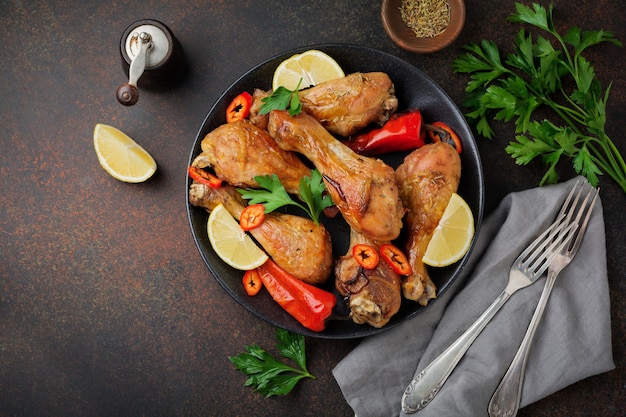 Stinchi appuntiti di pollo fritto in una padella di ghisa su una superficie di cemento o pietra scura. messa a fuoco selettiva vista dall'alto.