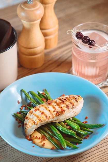 fried chicken sauce and green beans on the blue plate with blackberry alcohol cocktail on the table