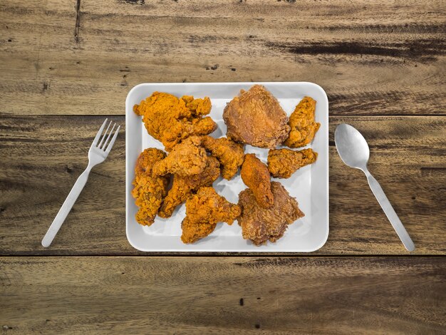 Fried chicken on white plate served on table. Concept of eating a lot.