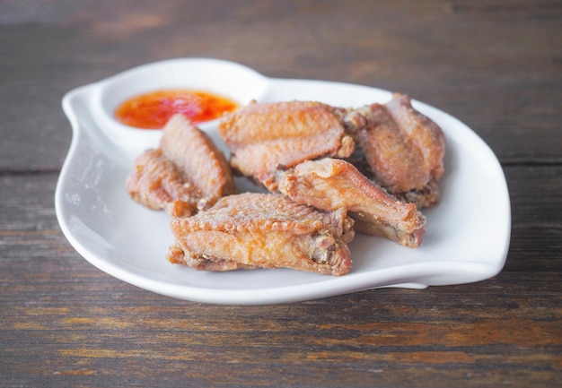 Жареное куриное крылышко с солью и острым соусом на белой тарелке