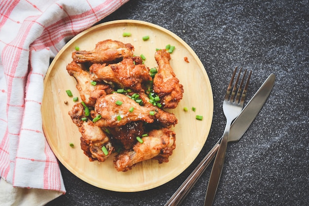 Fried chicken wings crispy salt on wooden plate with fork knife in the dining tabl