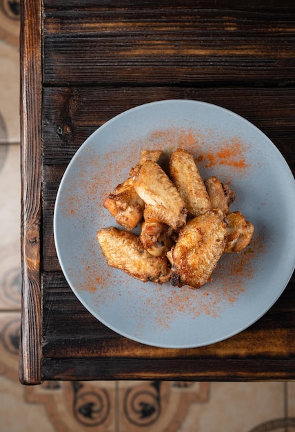 Fried chicken wings in a plate on a wooden table