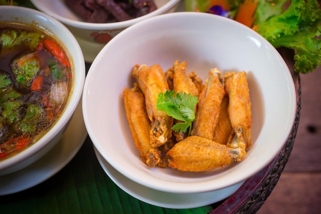 Fried chicken wings put in a white bowl topped with coriander leaves good taste and delicious