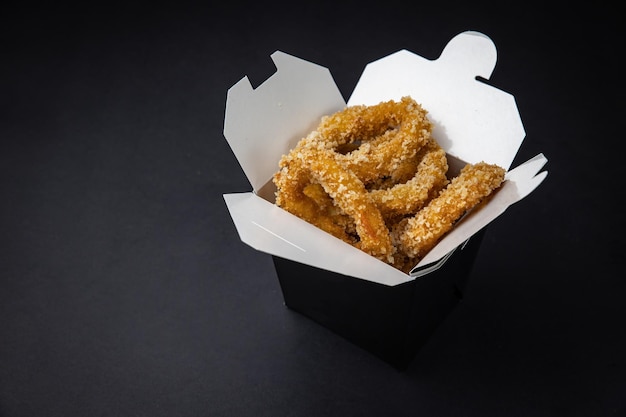 fried chicken wings with sauce and cheese in a delivery box on a black background