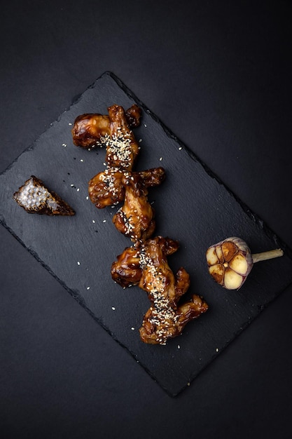 fried chicken wings with sesame seeds and spices on black background