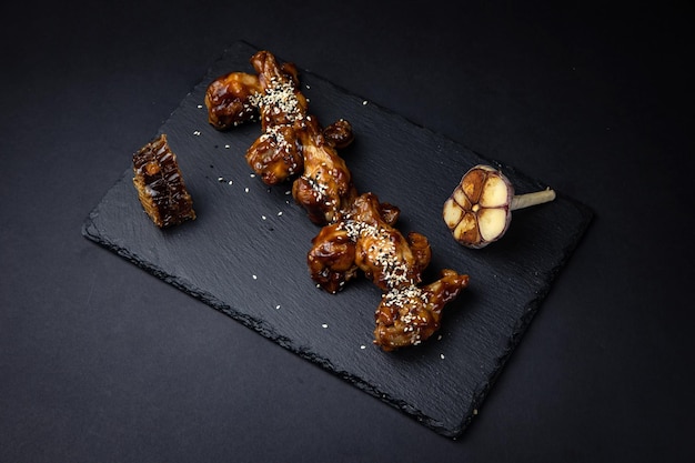 fried chicken wings with sesame seeds and spices on black background