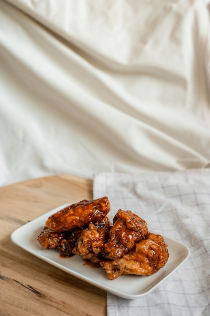 Fried chicken wings with spicy sauce on cutting board