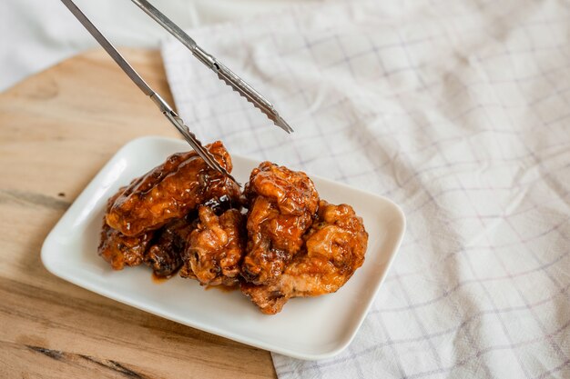 Fried chicken wings with spicy sauce on cutting board