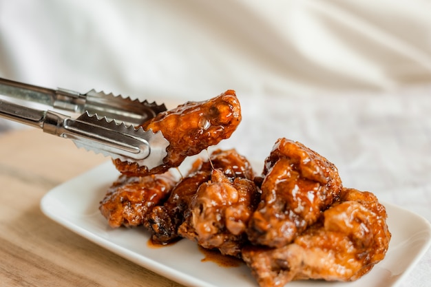 Fried chicken wings with spicy sauce on cutting board