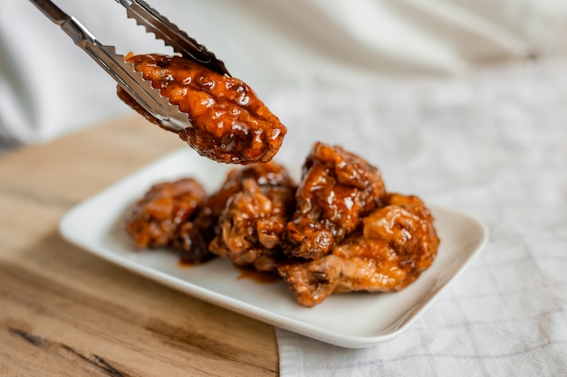 Fried chicken wings with spicy sauce on cutting board