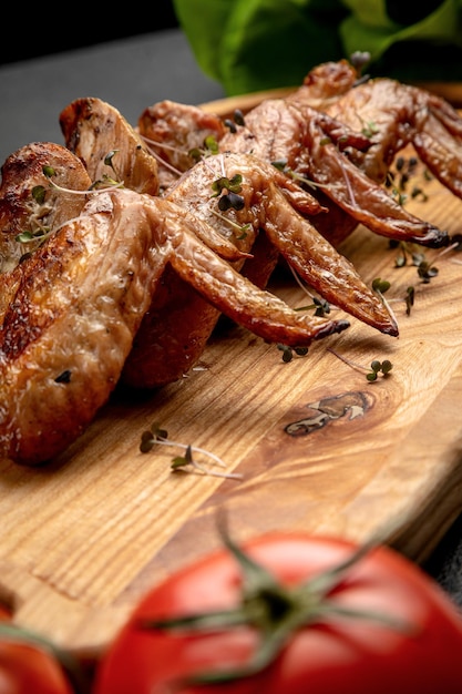 Foto ali di pollo fritte su una tavola di legno su uno sfondo scuro