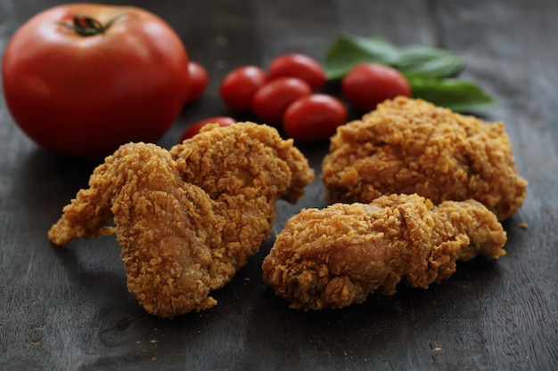 Fried Chicken with tomato in darken wood background