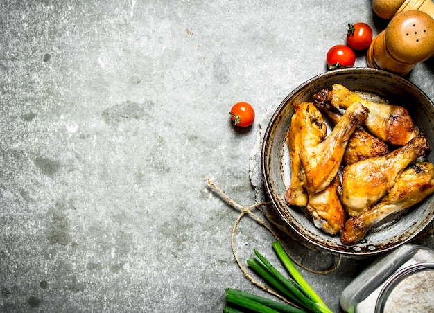 Fried chicken with vegetables and tomato sauce on a stone background