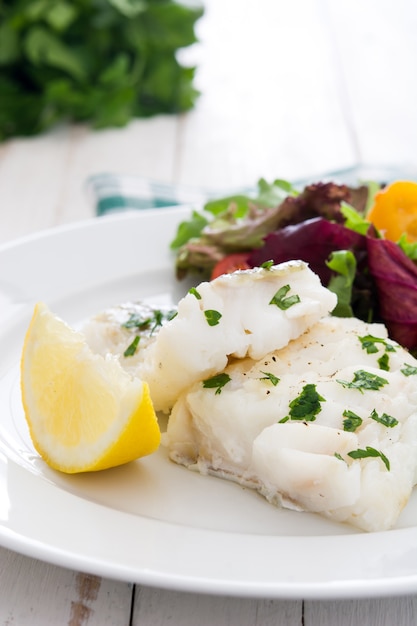 Fried cod fillet and salad in plate