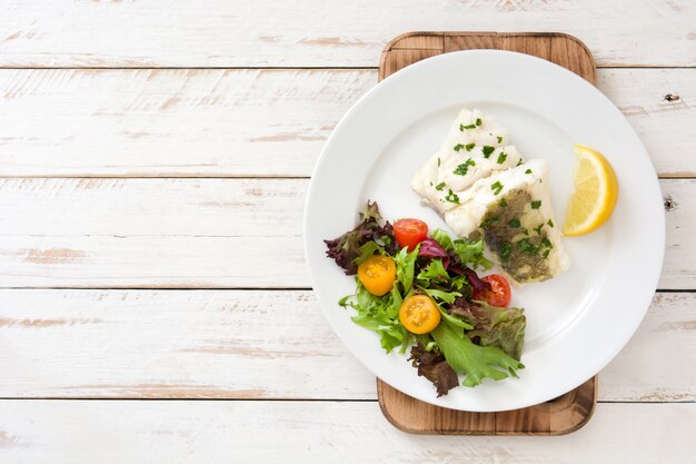 Photo fried cod fillet and salad in plate