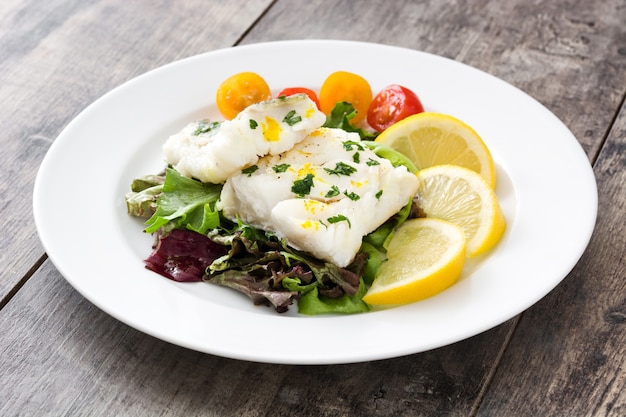 Fried cod fillet and salad in plate