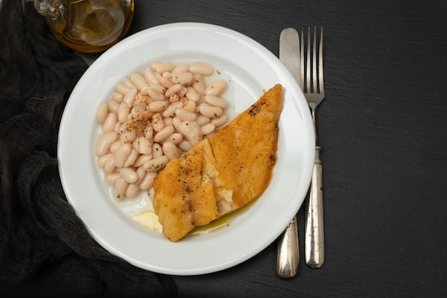 Fried cod fish with white beans on the plate