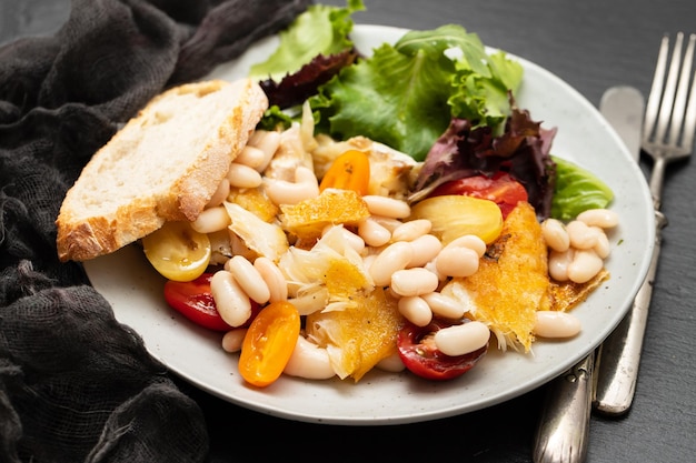 Fried cod fish with white beans on the plate