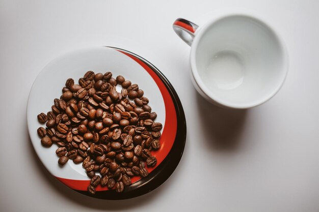 Fried coffee beans and white cup isolated on white background\
vintage photo processing