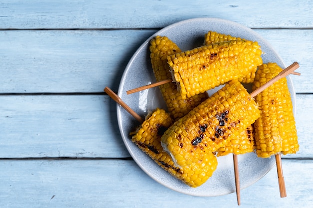 Fried corn on a light plate and a blue wooden table top view copy space