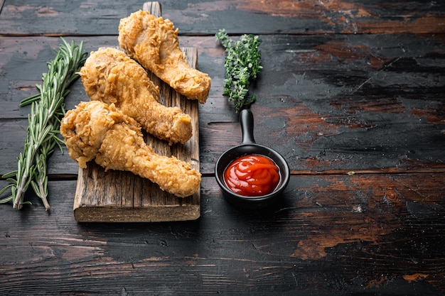 Fried crispy chicken legs, drumstick parts on dark wooden background