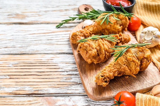 Fried crispy chicken legs on a wooden board