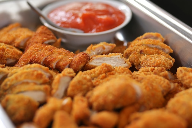 Fried crispy chicken nuggets with french fries and ketchup on white board