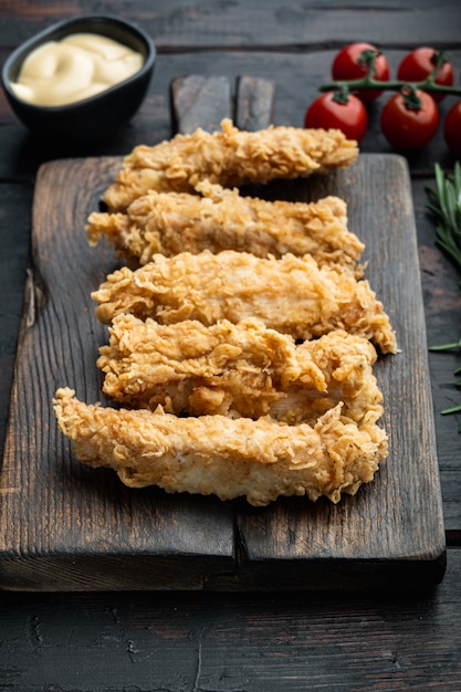 Foto parti di strisce di pollo croccanti fritte sulla vecchia tavola di legno scuro