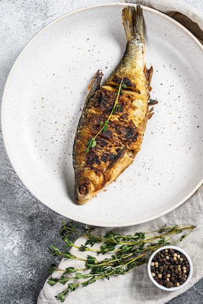 Fried crucian carp on a white plate. River organic fish. Top view