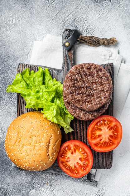 木の板に野菜とスパイスとハンバーガーの揚げコートレット白い背景上面図