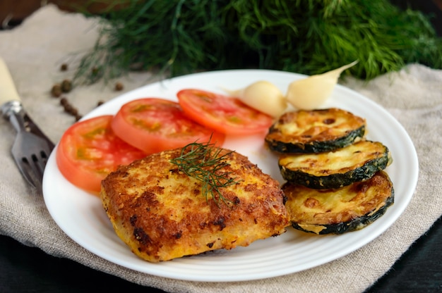 Fried cutlet, tomato and zucchini on a white plate