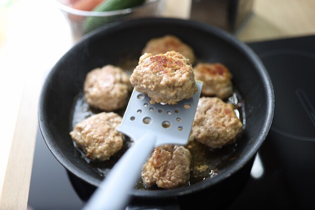 Fried cutlets with spatula are in frying pan