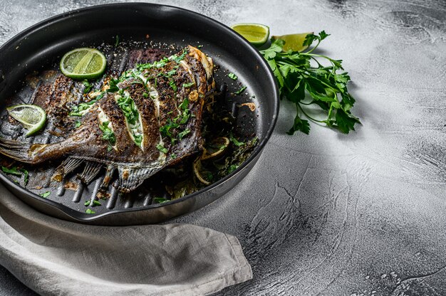 Photo fried dory fish with lime and parsley in a pan.