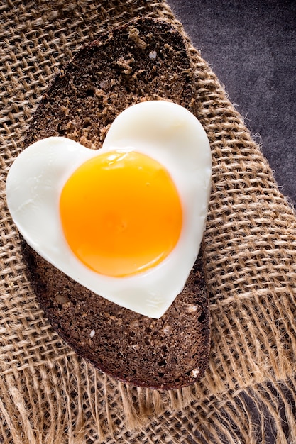 Fried egg on heart-shaped slice of bread.