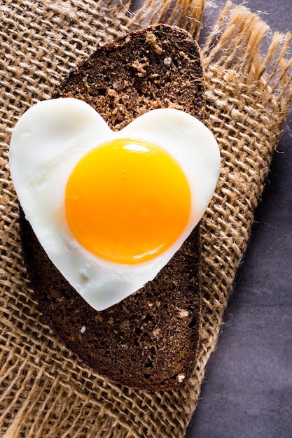 Fried egg on heart-shaped slice of bread.